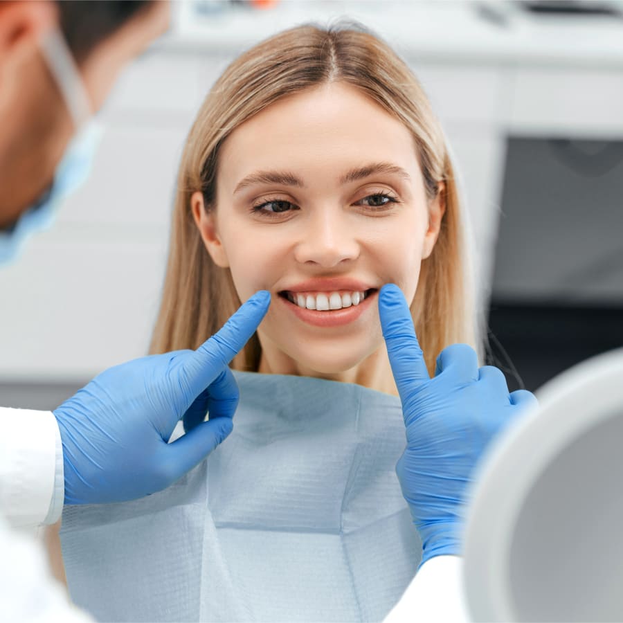 A dental assistant is smiling brightly as she passes someone a clipboard.