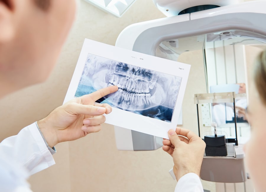 A dentist points to a panoramic X-ray.